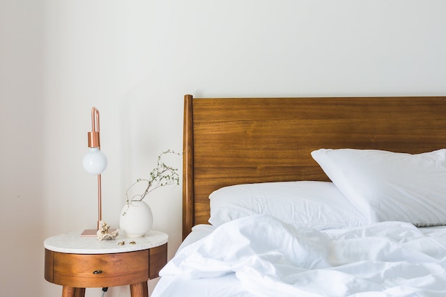 bed%20with%20a%20wooden%20frame%20and%20white%20sheets%20next%20to%20a%20night%20table%20with%20a%20lamp%20and%20a%20small%20plant%20on%20it bed with a wooden frame and white sheets next to a night table with a lamp and a small plant on it